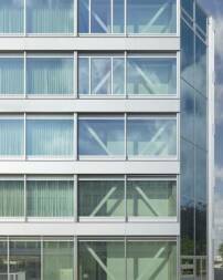 Sichtbare Konstruktionselemente und Pfosten-Riegel-Fassade mit horizontal gliedernden Aluminiumpaneelen und Glas als uere Gestaltungsmerkmale 
